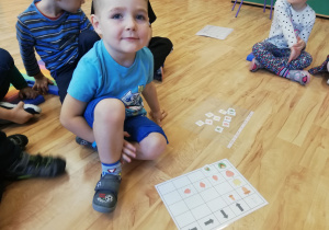 Chłopiec układa jesienne symbole zgodnie z podanym kodem